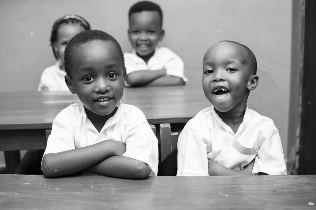 Black and white photo of joyful African children smiling in a classroom.