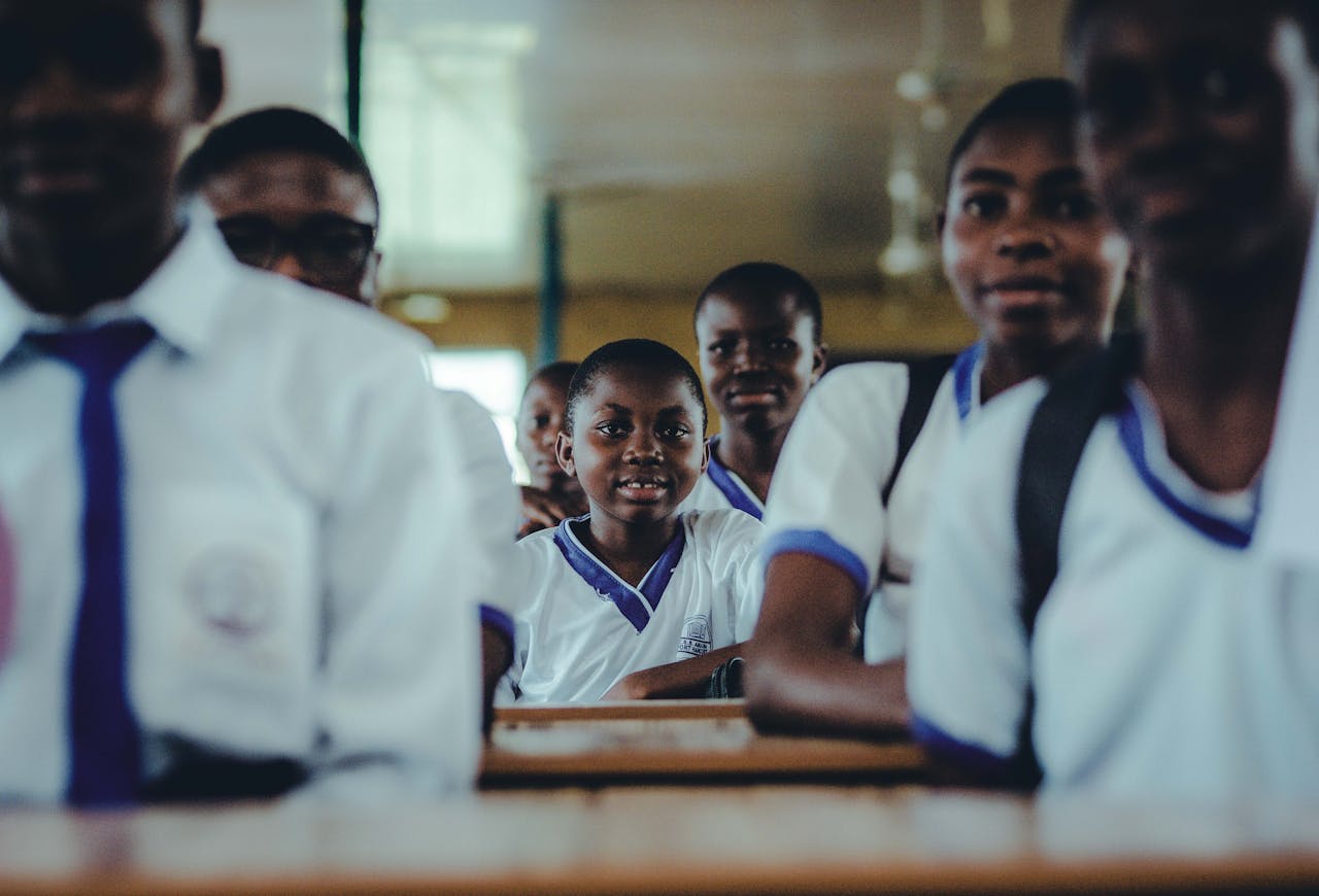 gallery-6 A group of Nigerian schoolchildren in uniform sitting in a classroom, engaging in learning.